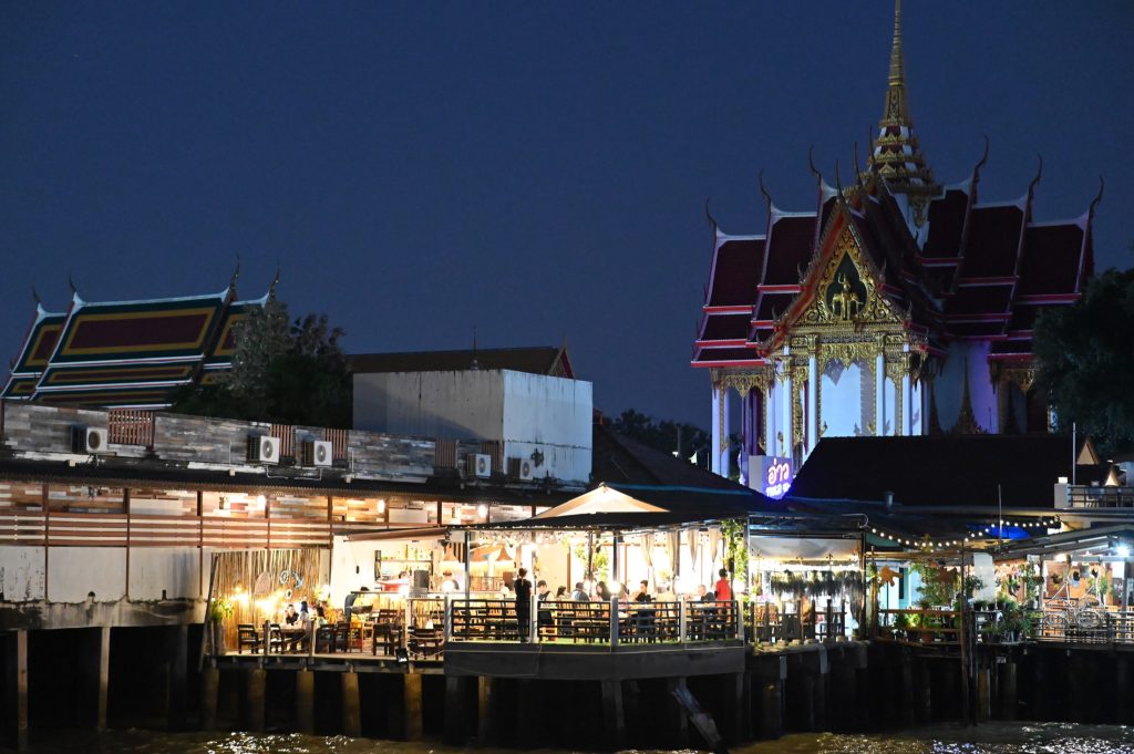 曼谷河边餐饮区与寺庙夜景，适合说明傍晚雨天河边氛围和晚餐衔接