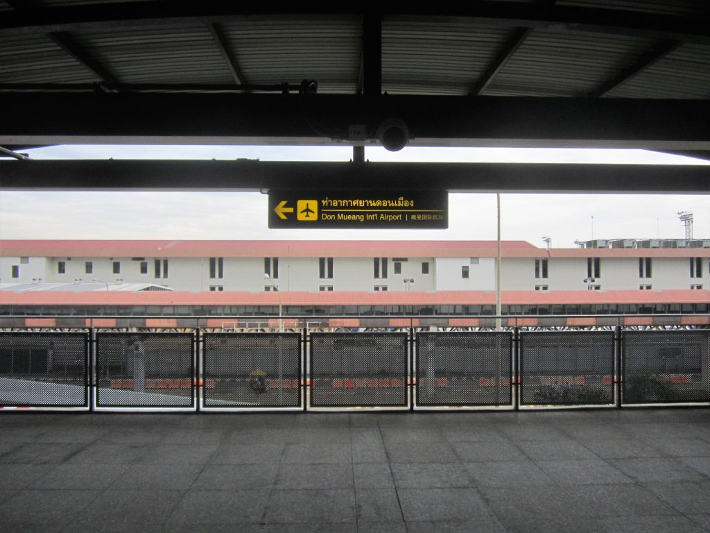 廊曼红线站连接层的黄色机场方向牌指向 Don Mueang International Airport