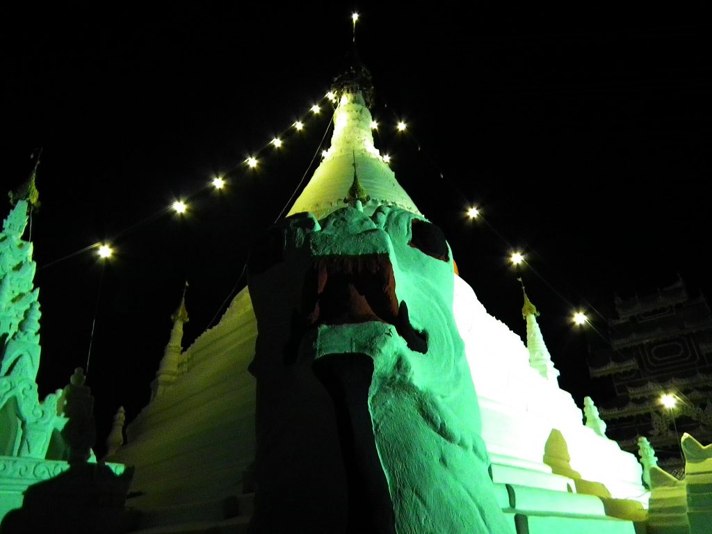 夜间绿色灯光照亮帕塔多伊功穆寺白塔与守护狮像