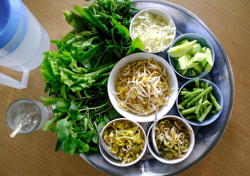一盘南部泰餐常见的生鲜蔬菜与香草，包含多种绿色叶菜、豆类和黄瓜