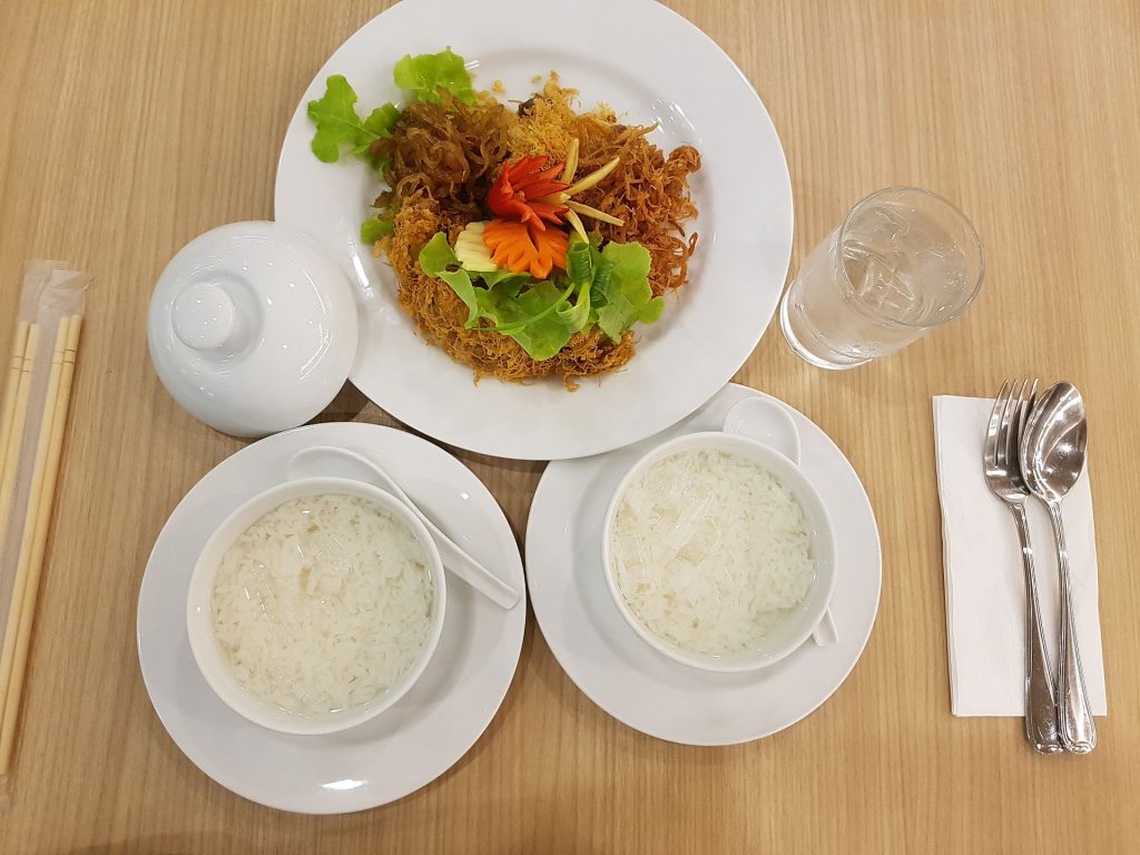 木桌上的考切套餐包含两碗冰水米饭、一盘甜咸配菜、白色茶壶和餐具