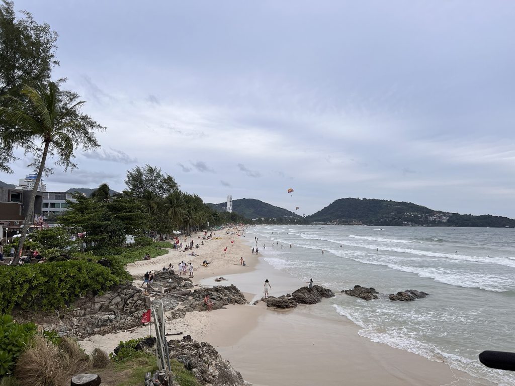 阴天的普吉芭东海滩、近岸礁石与沿岸建筑