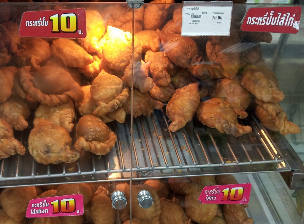 泰国便利店玻璃柜中分层摆放的金黄色咖喱角
