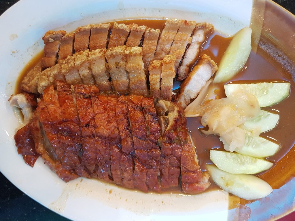 白盘里的烧鸭和脆皮猪肉切片配黄瓜