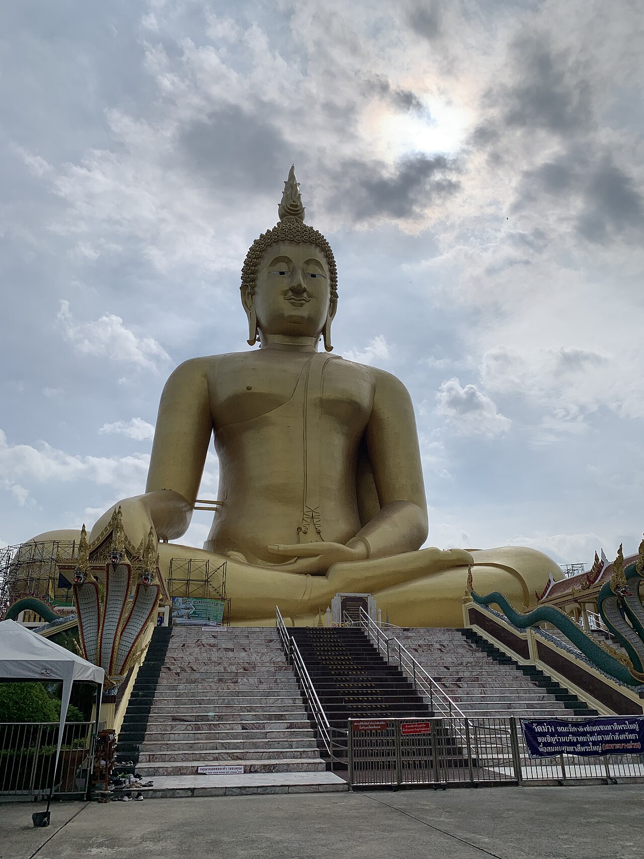 红统大佛正面全景,金色坐佛在蓝天下