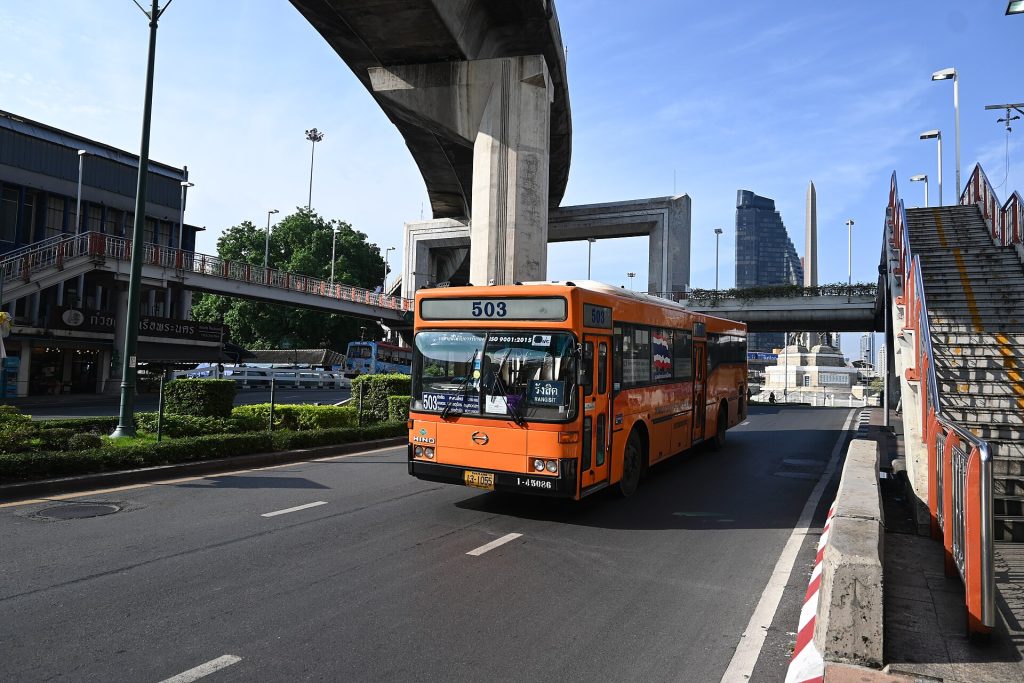 曼谷胜利纪念碑高架桥旁行驶的橙色 BMTA 503 路公交车