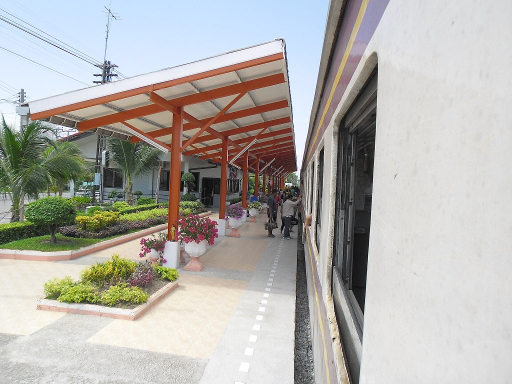 列车旁的芭提雅站橙白色雨棚、花坛与单层站房