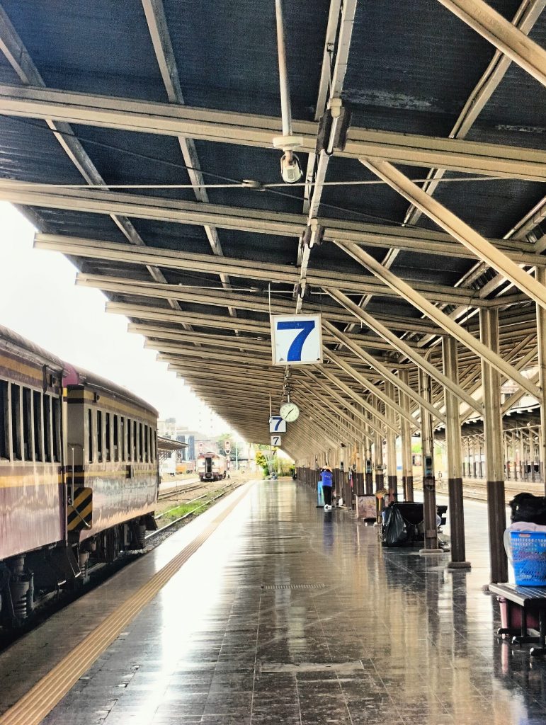 华喃峰火车站七号站台旁停着客车，金属顶棚向远处延伸