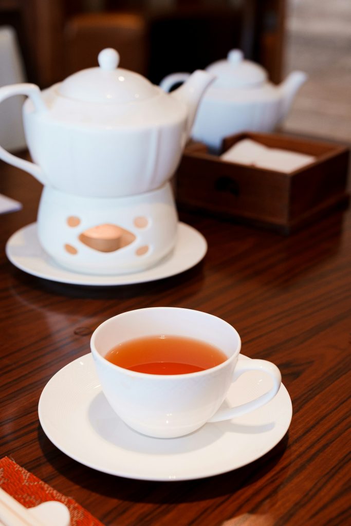 木桌上的白瓷茶壶、茶炉与一杯红茶