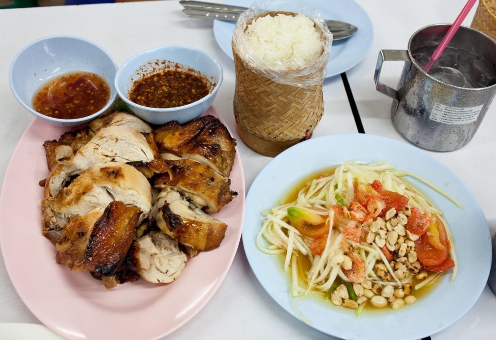 粉色盘装切块烤鸡配青木瓜沙拉糯米饭与两碟酱