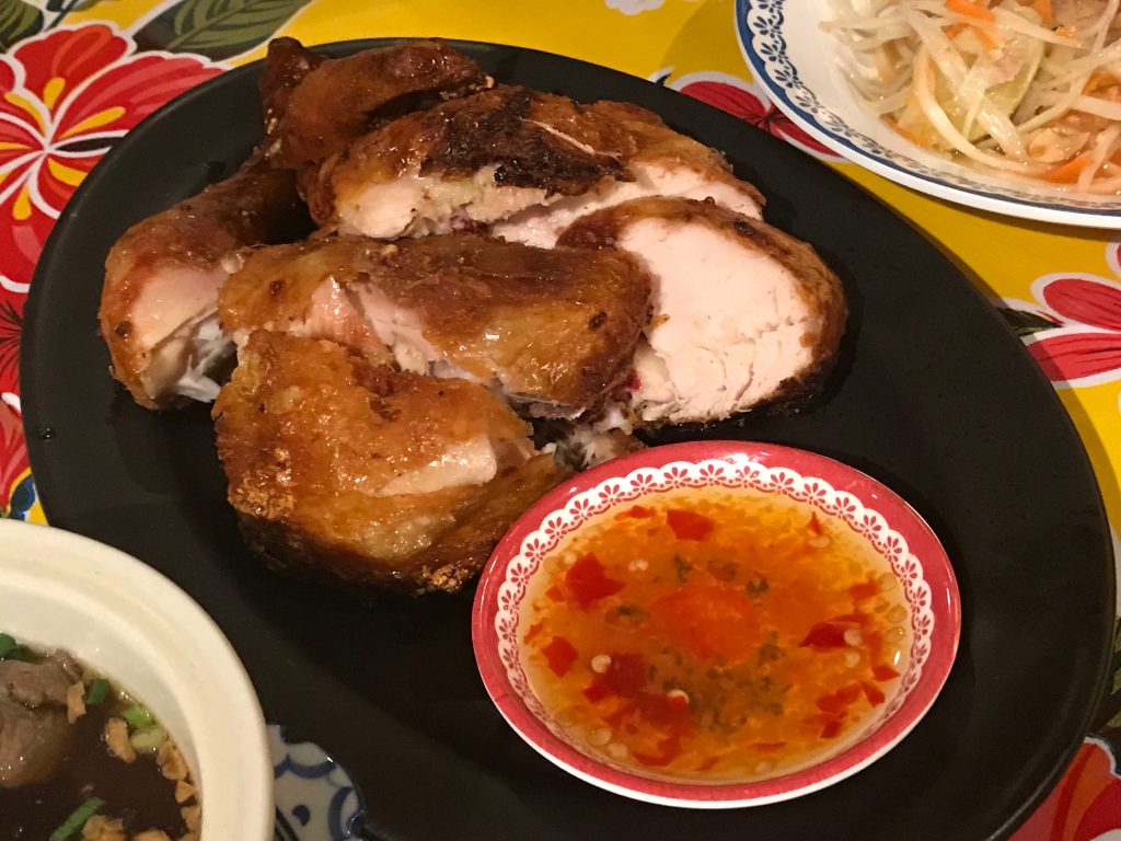 黑盘中切开的焦褐色烤鸡配一小碟橙红蘸酱