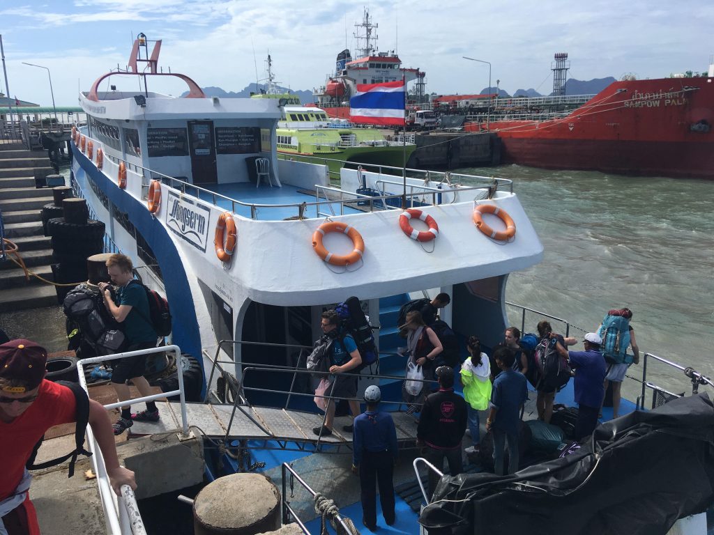 东萨码头一艘白蓝色客船靠泊，旅客正在登船，后方还有红色渡轮