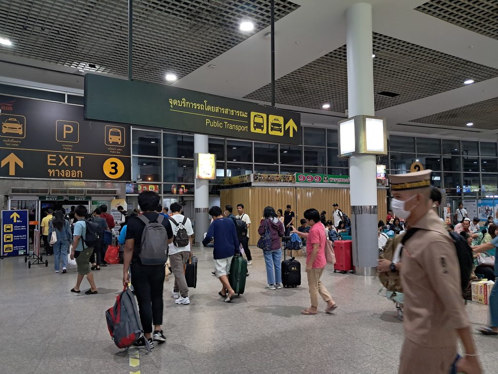 莫奇二号室内出口指示牌下，多名旅客拖着行李穿过大厅