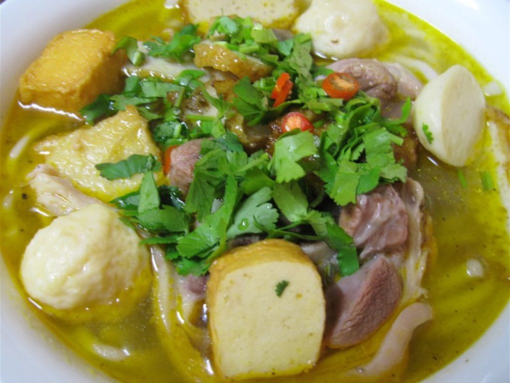 一碗越南粗面汤配有肉块、鱼丸、豆腐、香菜与红辣椒