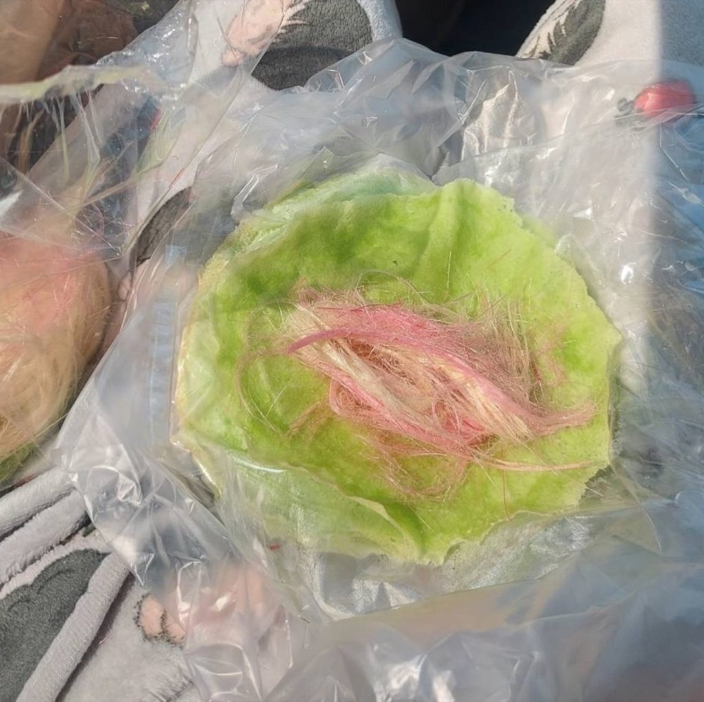 绿色薄饼中央放着粉色与浅色糖丝