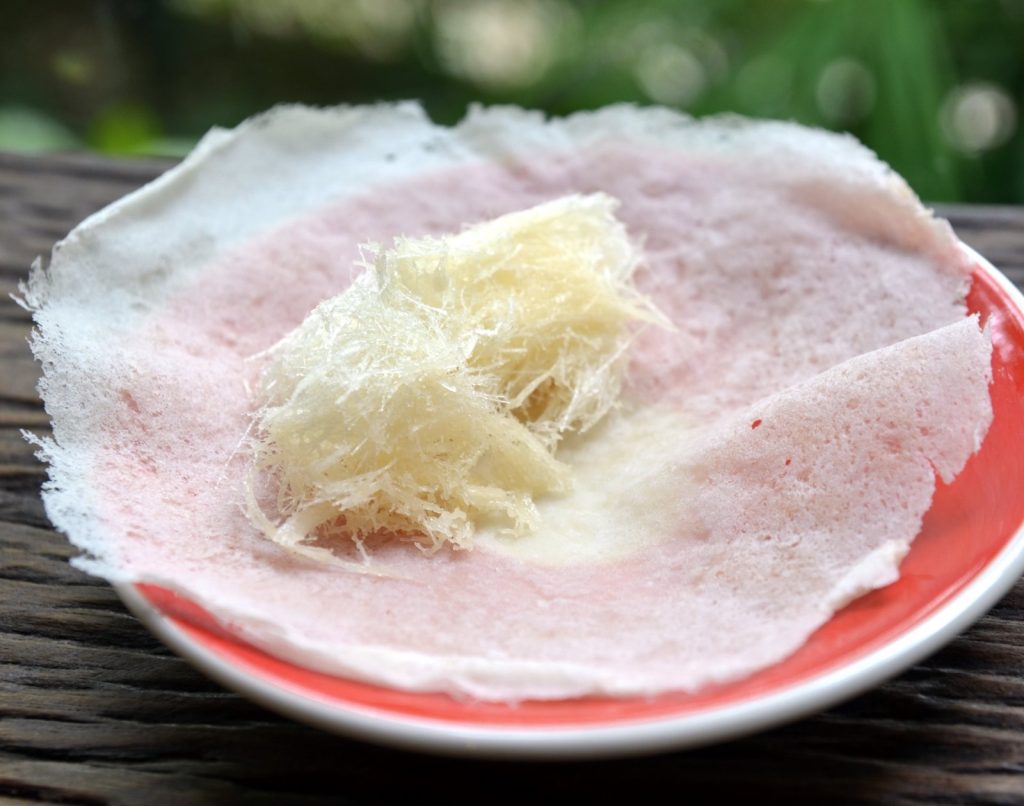 红盘中的浅色薄饼托着一团淡黄色糖丝