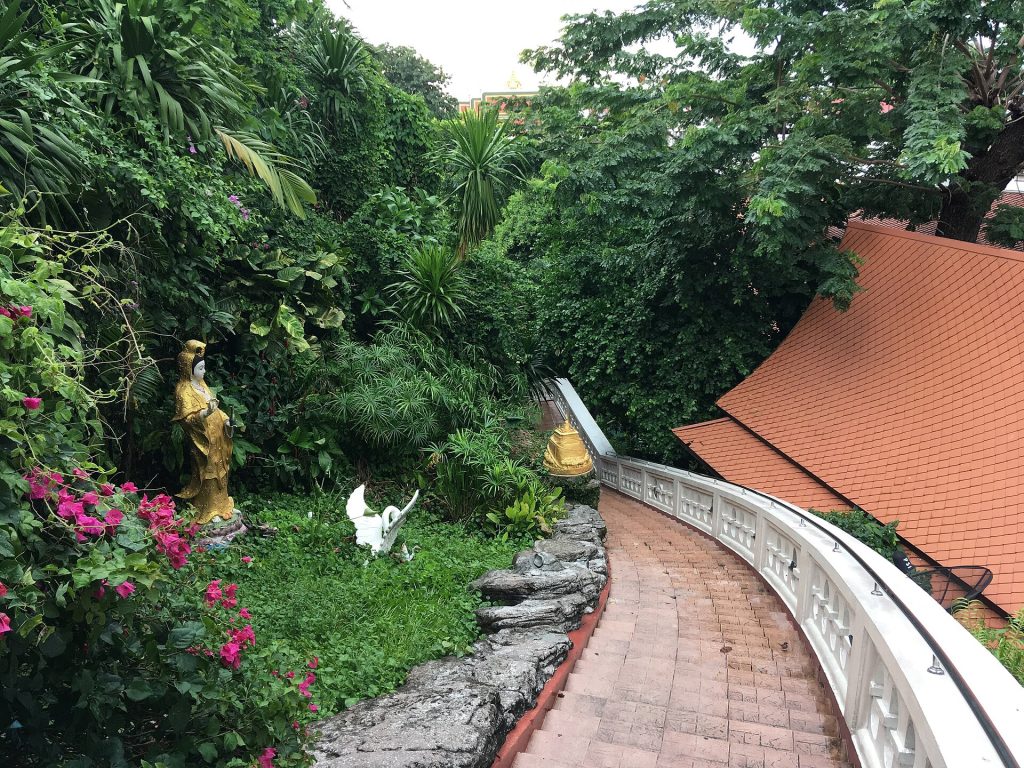 金山寺红砖色台阶沿白色栏杆转弯，旁边有茂密绿植和立像