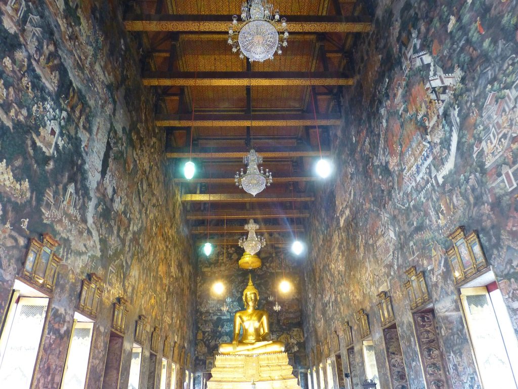 苏泰寺戒堂内的金色坐佛，四周高墙和后壁铺满人物、建筑与山水壁画。