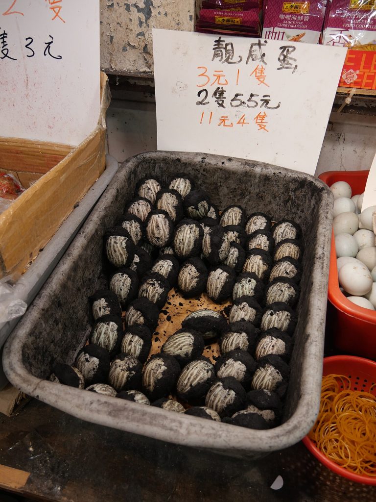 市场塑料箱里整齐摆放着裹有黑灰泥层的咸鸭蛋