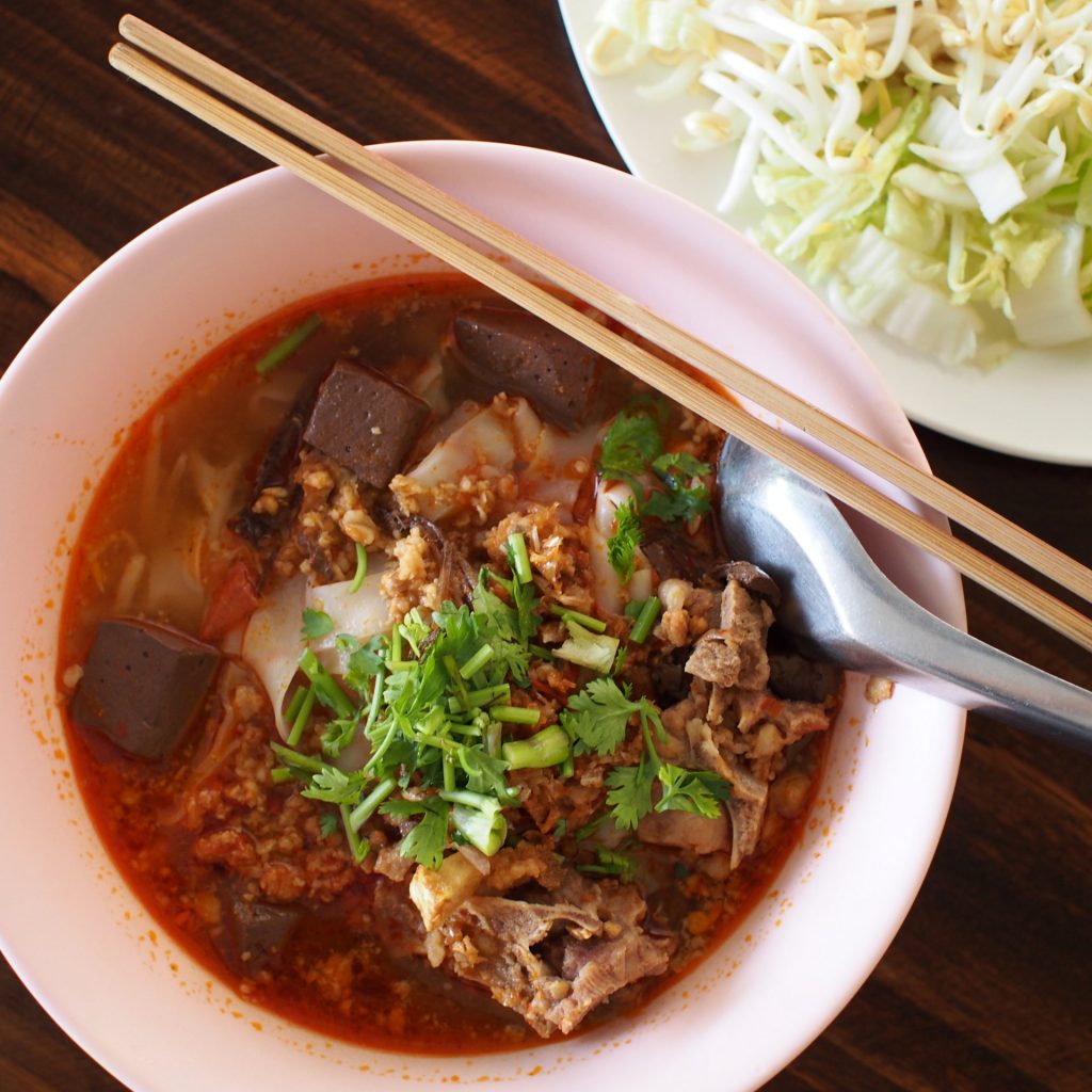 粉色碗中的宽米面、肉末与深色块状配料，旁边另放豆芽