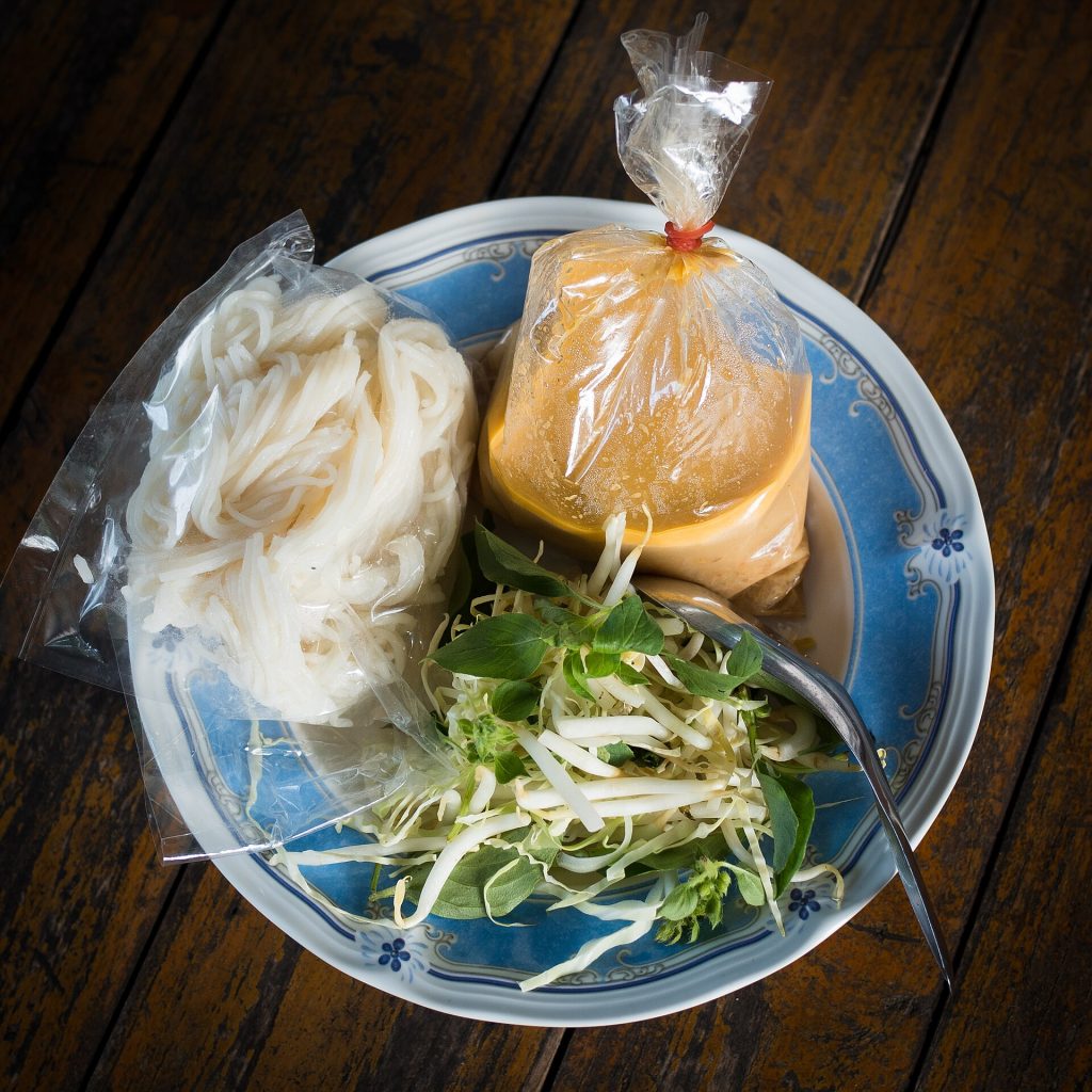 盘中分装的白米线、橙色酱汁和新鲜蔬菜
