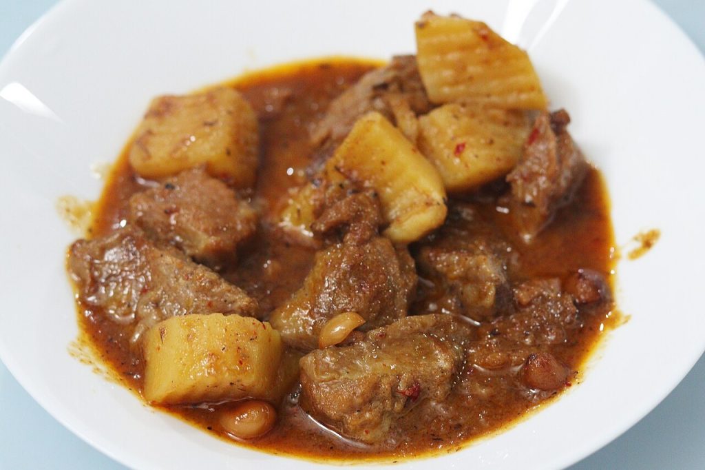 白盘里带肉块、土豆和花生的浓咖喱