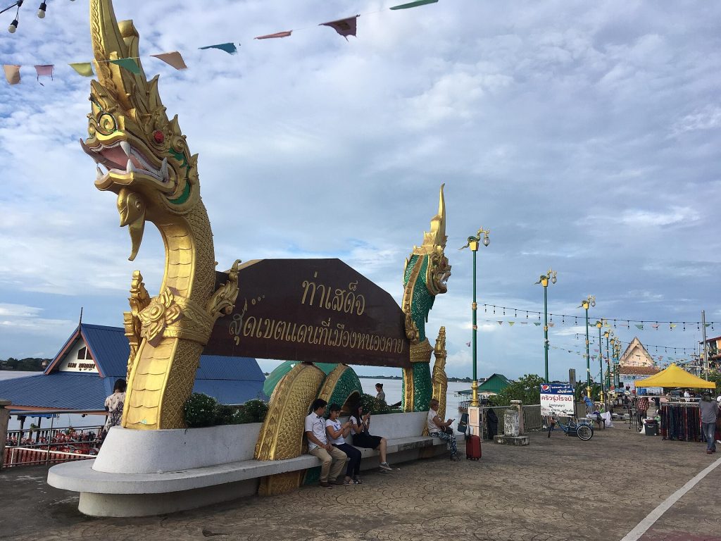 廊开湄公河岸一座金绿相间的纳迦雕像立在写有泰文的拱形座椅旁