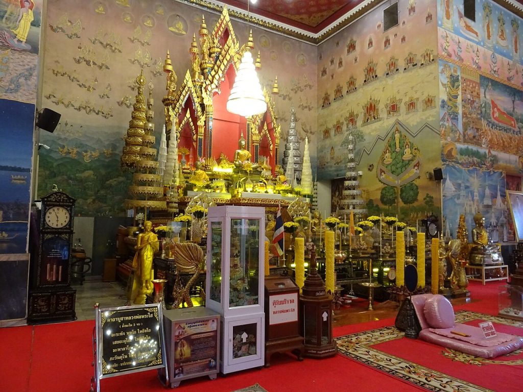 菩猜寺供台近景，金色佛像、白色伞盖和四周壁画