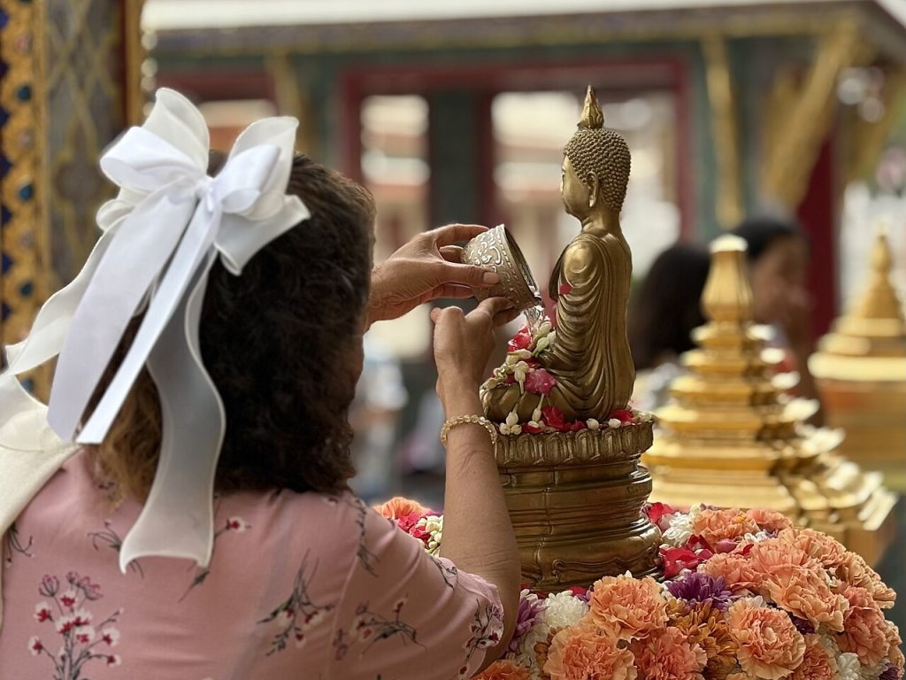 曼谷拉查波披寺参与者用银色杯子向坐佛浇水