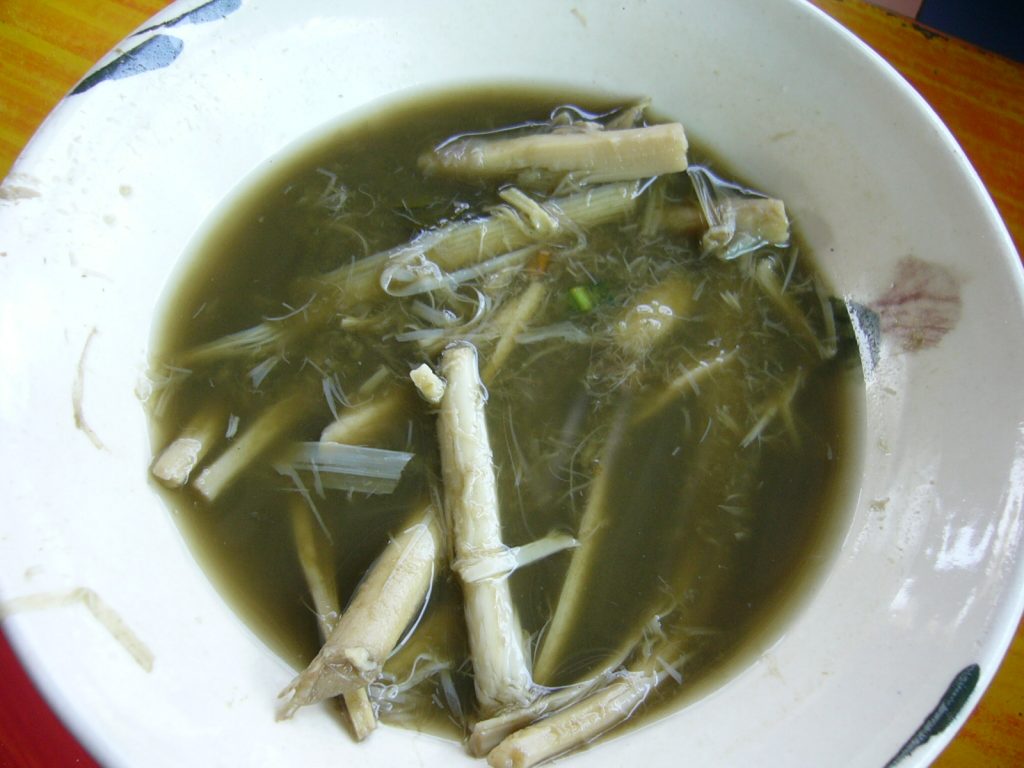 白碗中的泰式竹笋汤有浅色笋条和深绿色汤汁
