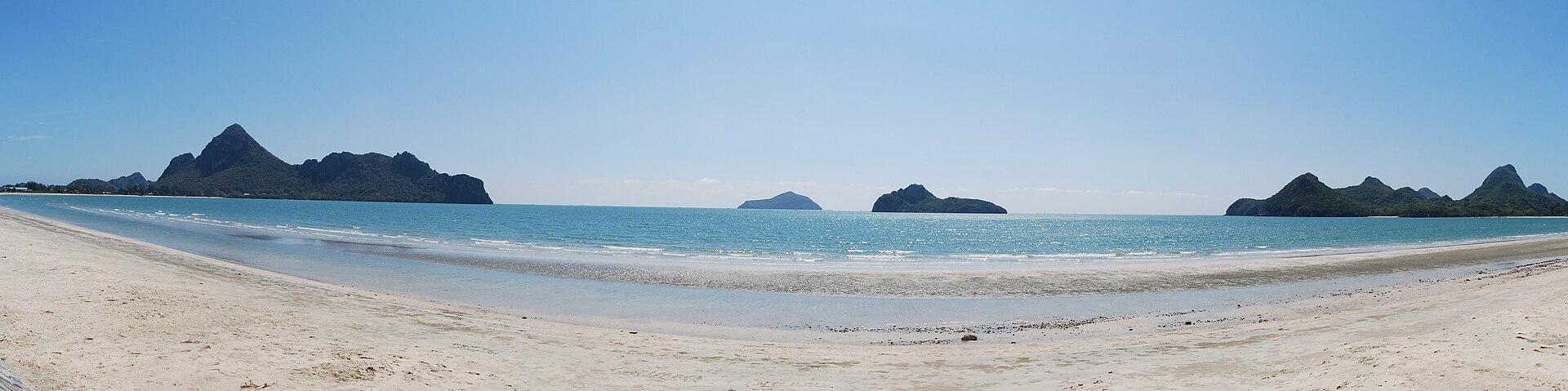 奥玛瑙湾白色沙滩横向展开，海面外分布着多座深色山岛