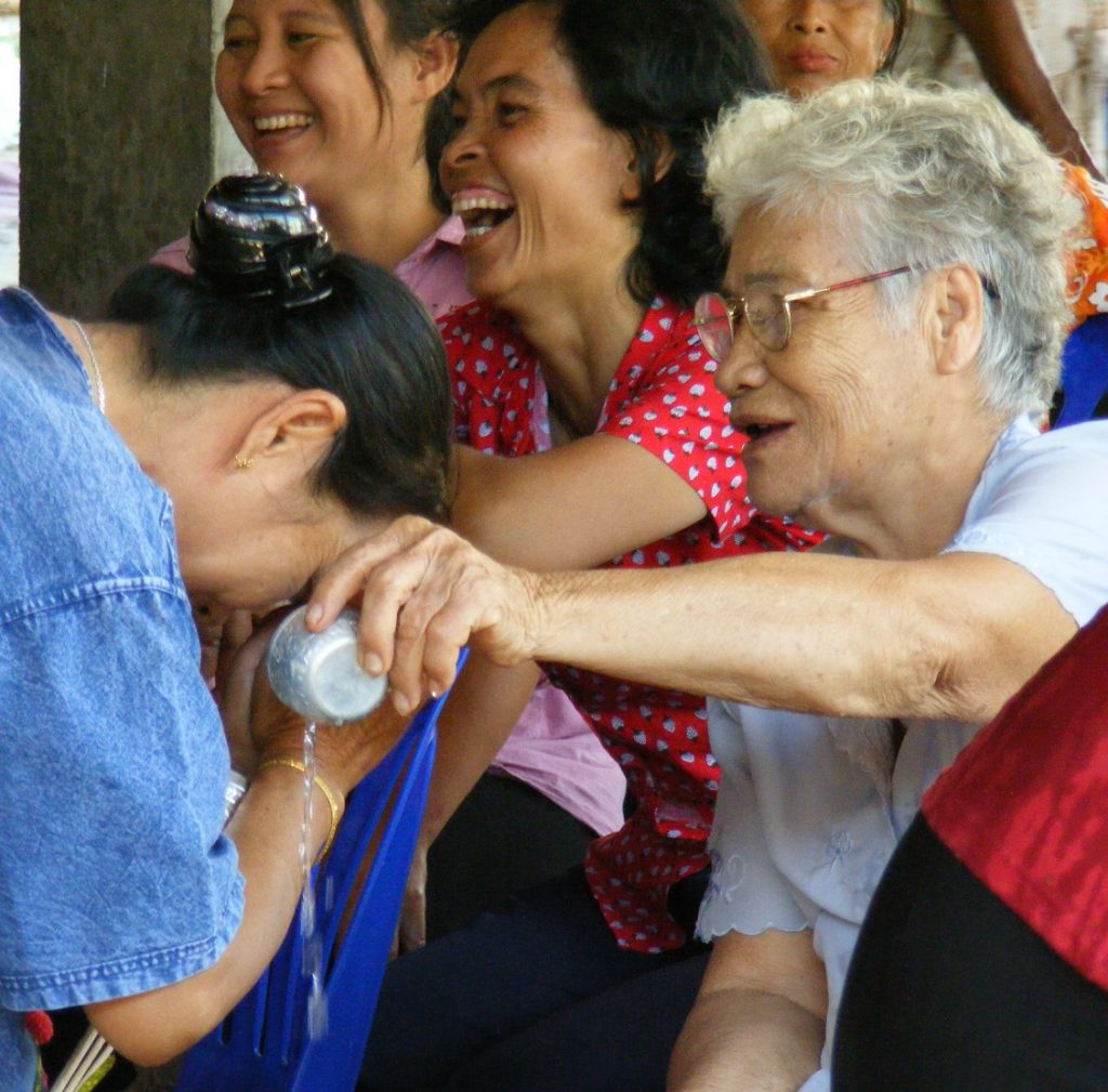 宋干节现场，一名白发女性将水倒在另一人的手上