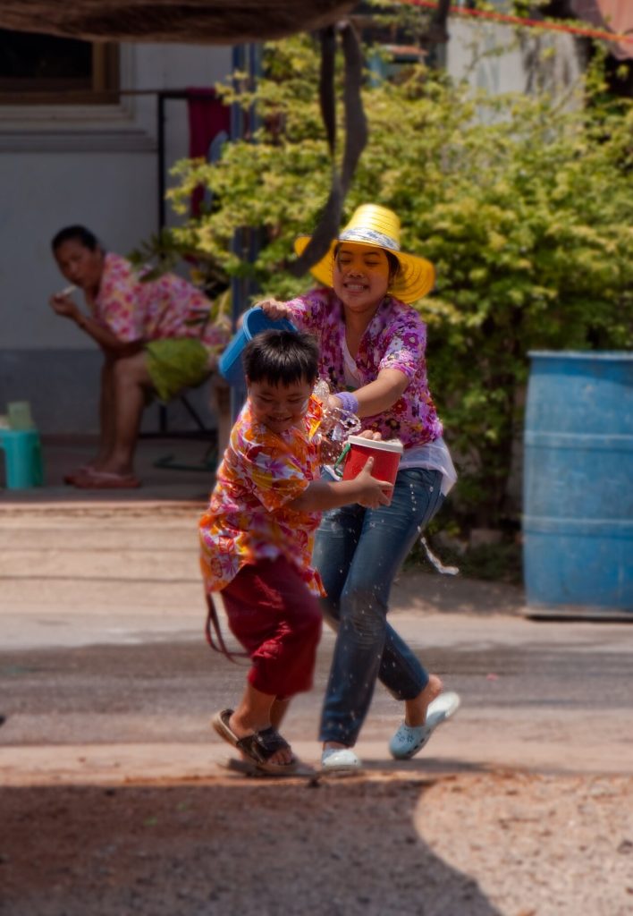 宋干节街头，一名女子向奔跑的孩子泼水