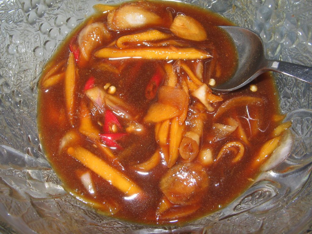 玻璃碗中带切片配料的棕色Budu酱汁