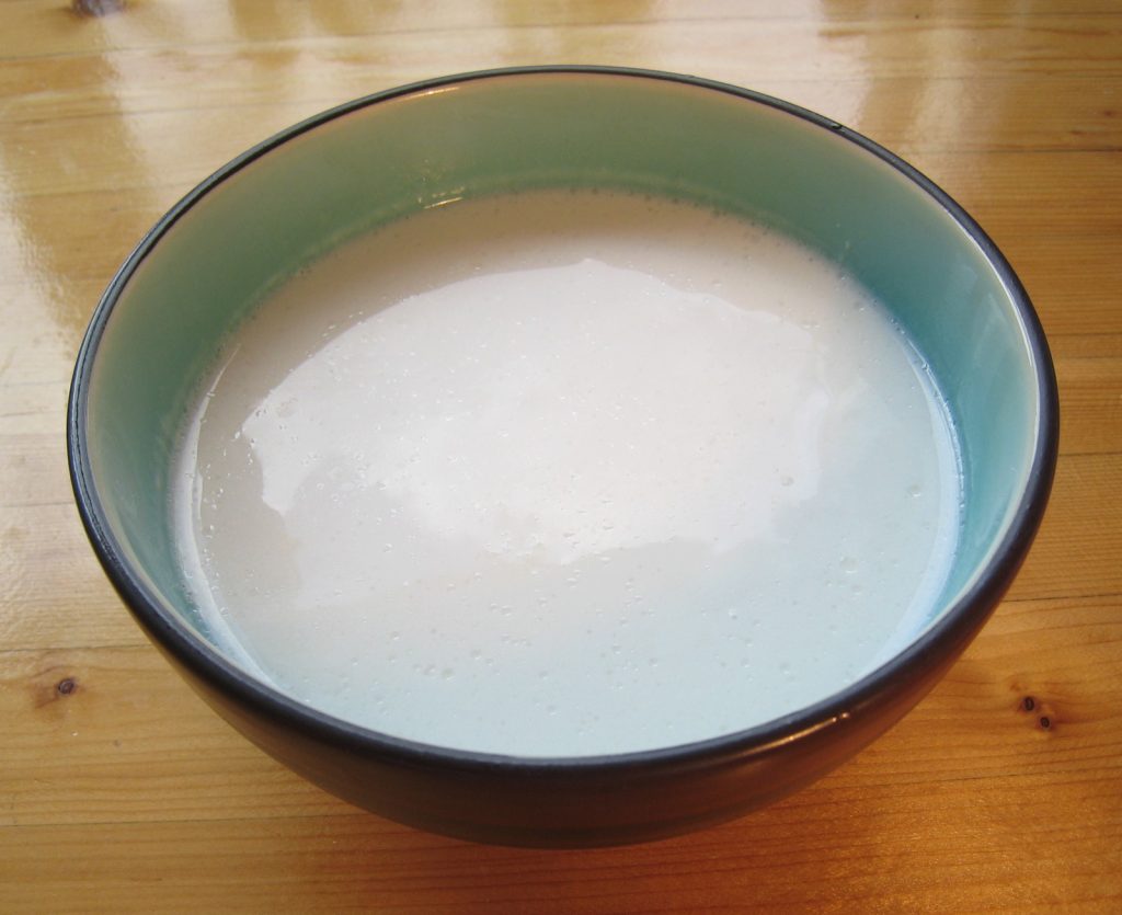 木桌上碗中乳白色的椰奶