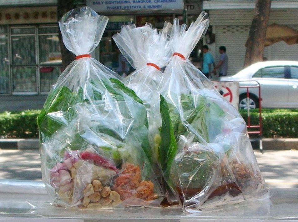 曼谷街边摊出售的透明袋装 Miang Kham 配料，可见叶片、花生和小虾干
