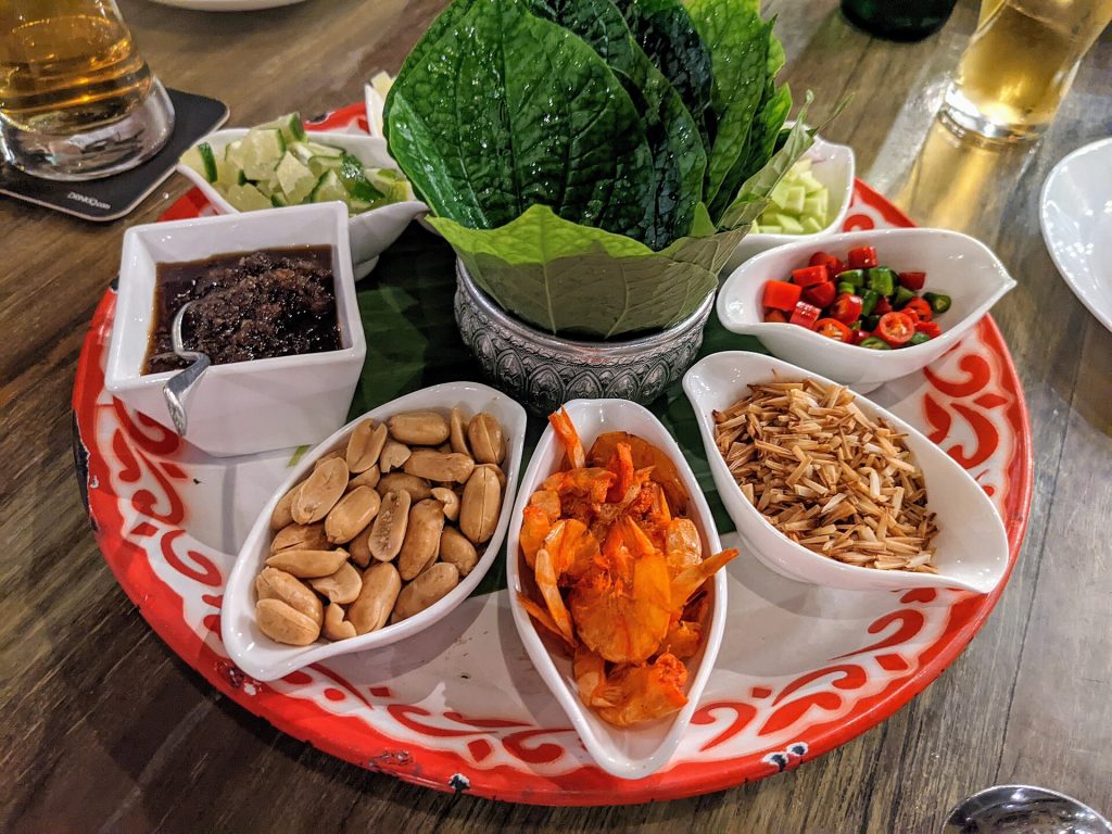 餐盘中分开放置的 Miang Kham 叶片、花生、小虾干、椰丝、辣椒和酱汁