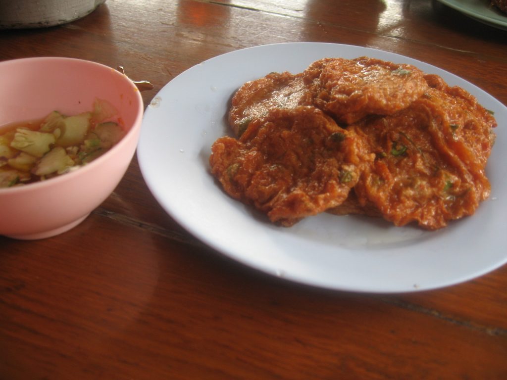 白盘中叠放橙褐色鱼饼，旁边粉色碗中可见黄瓜片。