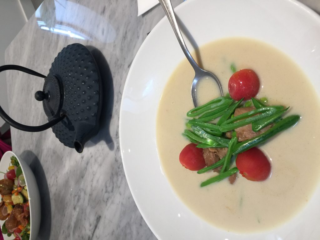 海外餐厅的椰奶鸡汤，中央摆有绿色蔬菜与红色番茄