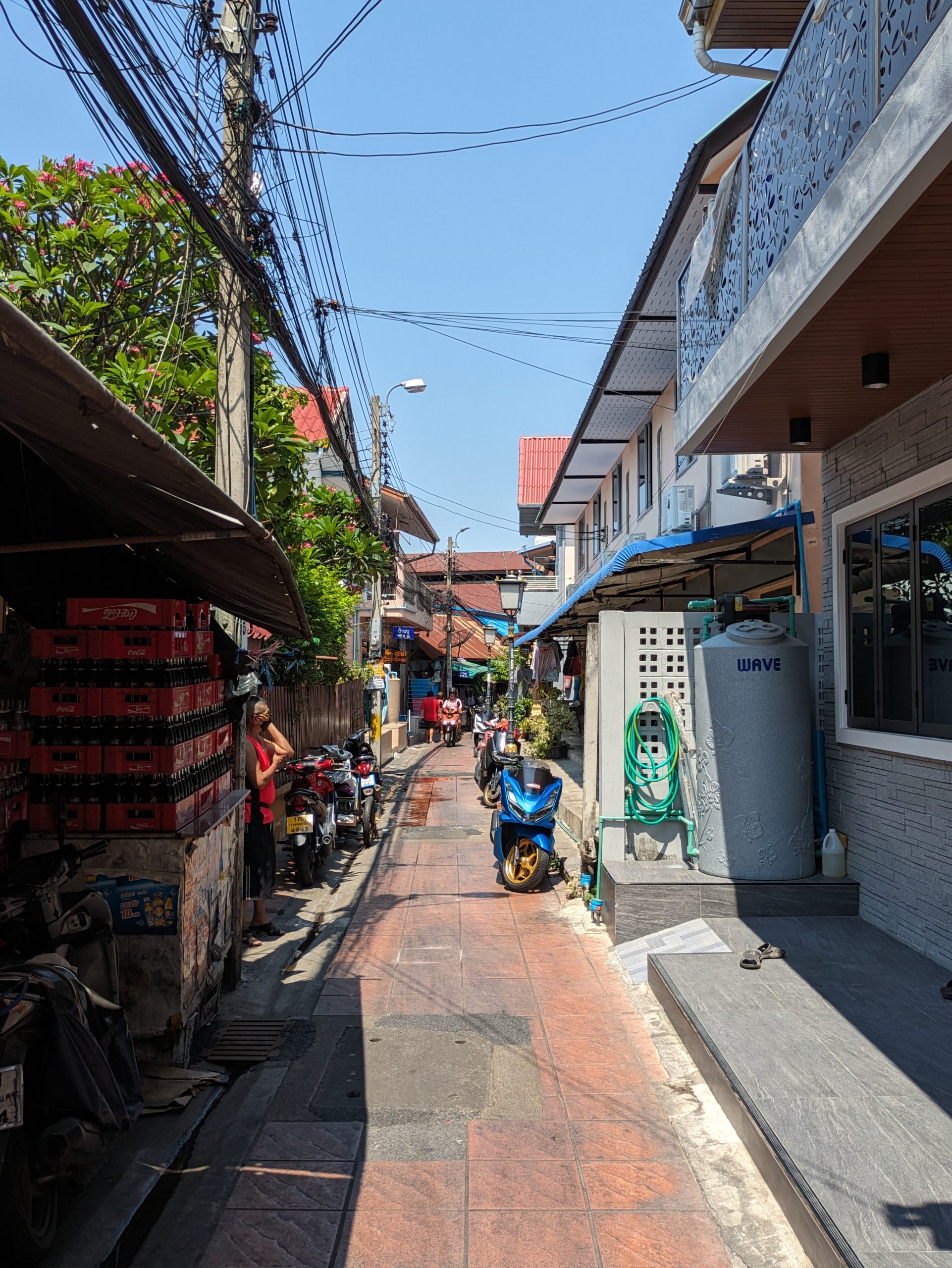 班布社区的现代街巷,路旁可见店铺、摩托车和电线。