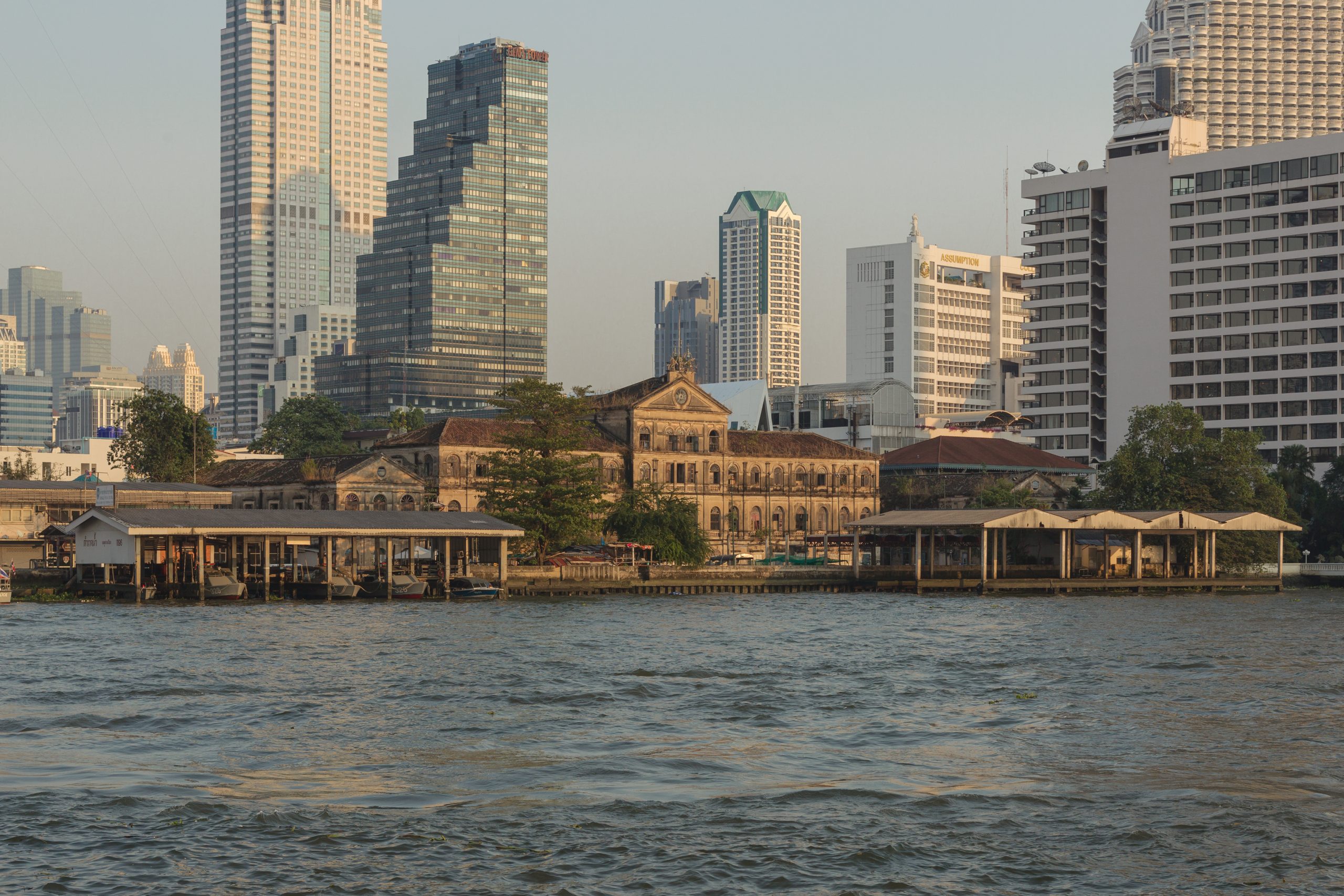 2019年的河面全景:旧海关中央钟楼与两侧长立面,近岸有棚屋和船。