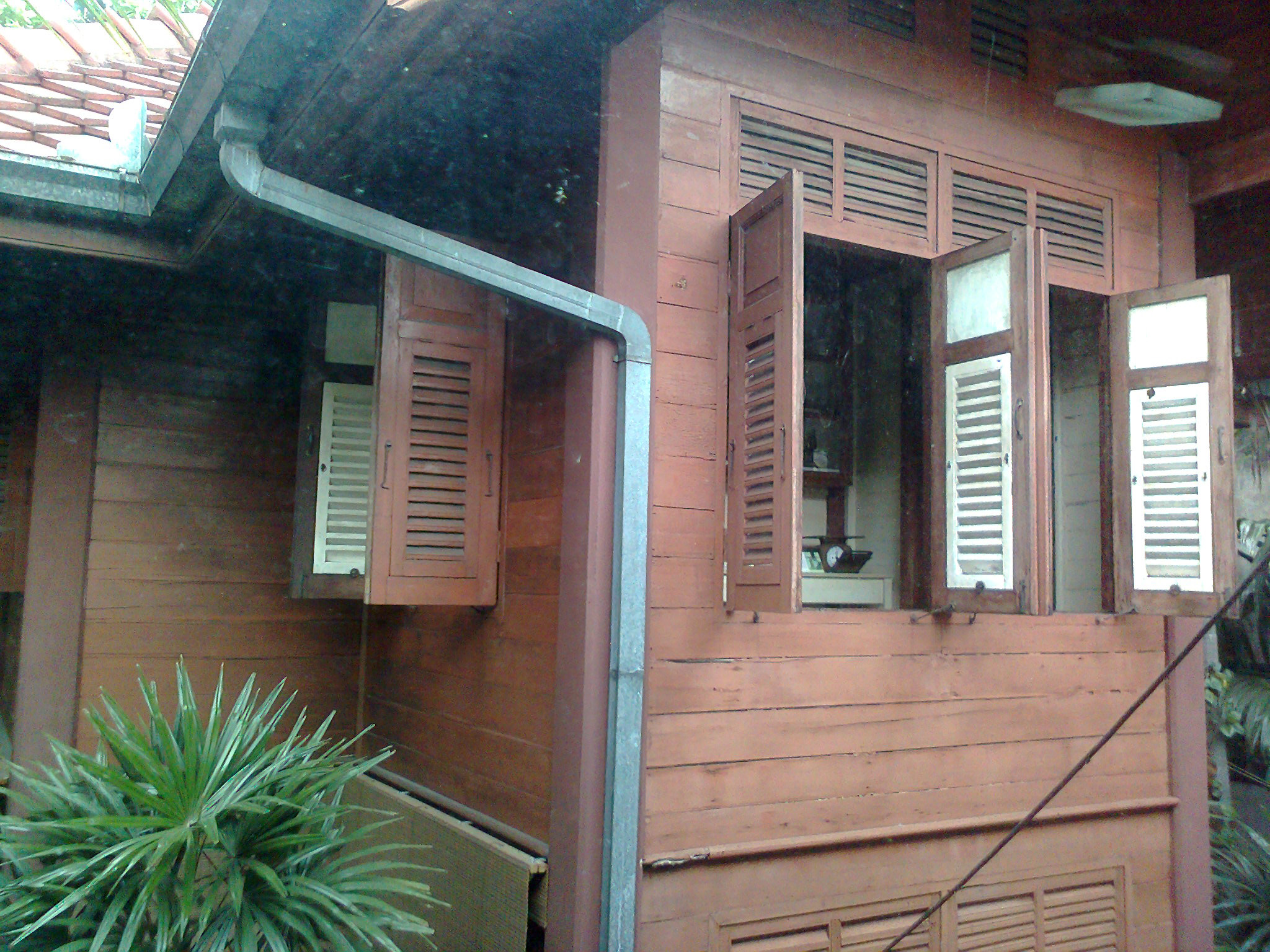 曼谷民俗博物馆第二栋木屋的棕红横木墙、外开窗、百叶板条和浅色雨水管，2013年2月拍摄