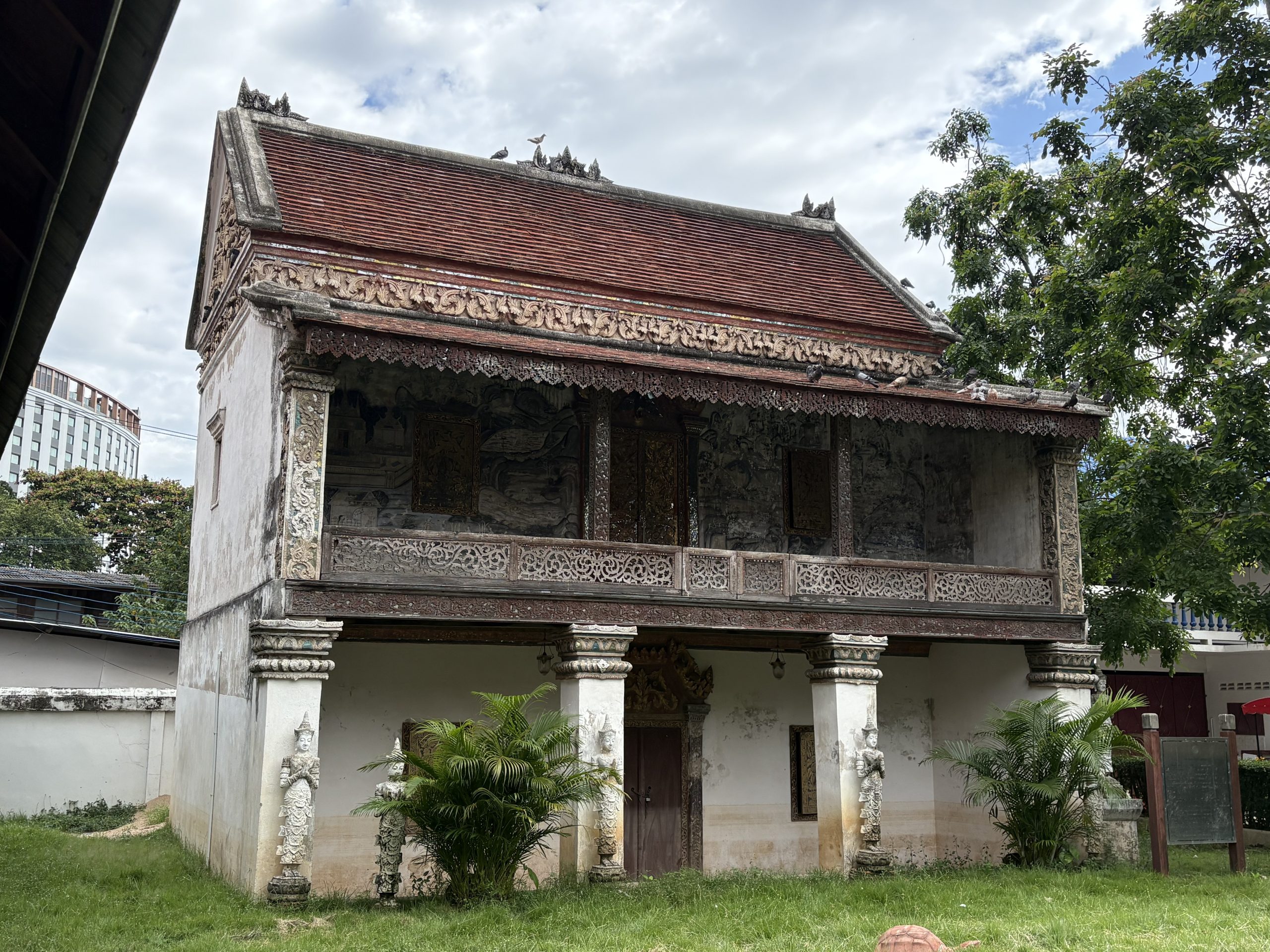 清迈 Wat Chang Khong 两层经楼，白墙下层、红瓦屋顶、金色门窗、上层墙画与透雕木栏