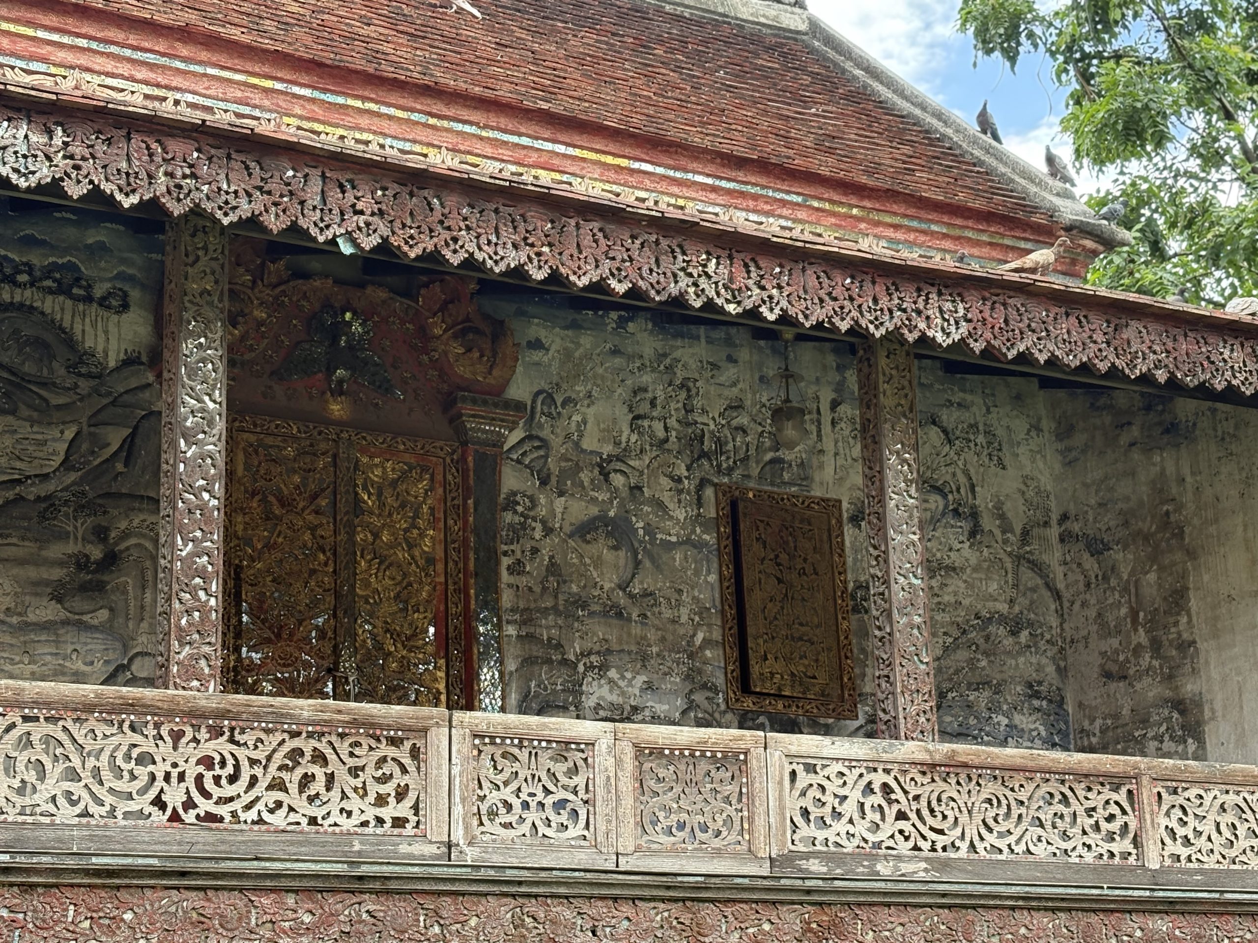 清迈 Wat Chang Khong 经楼上层右侧近照，金色双门、雕花木窗、褪淡的墙画与透雕栏板