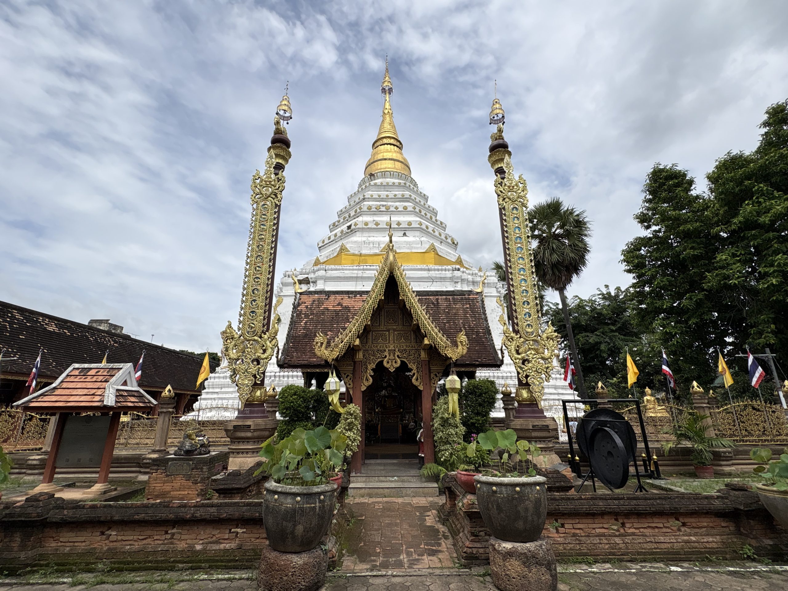 清迈 Wat Chiang Yuen 主塔，白色折角塔身、金色塔尖、塔前小建筑与两杆金色硬幡