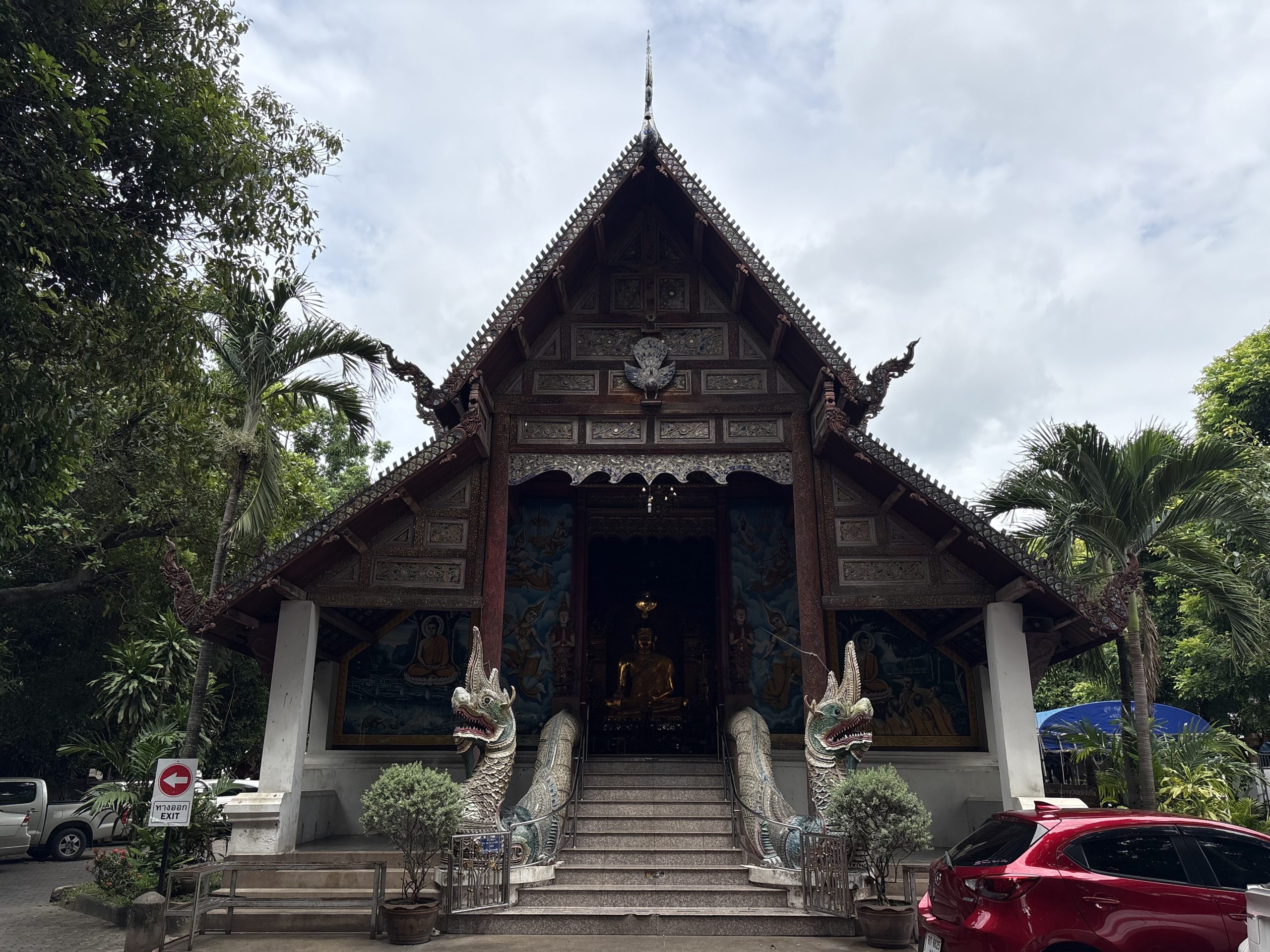 清迈 Wat Chiang Yuen 礼佛殿正面，孔雀山墙、绿白兽形阶栏、台阶与入口暗处金色佛像