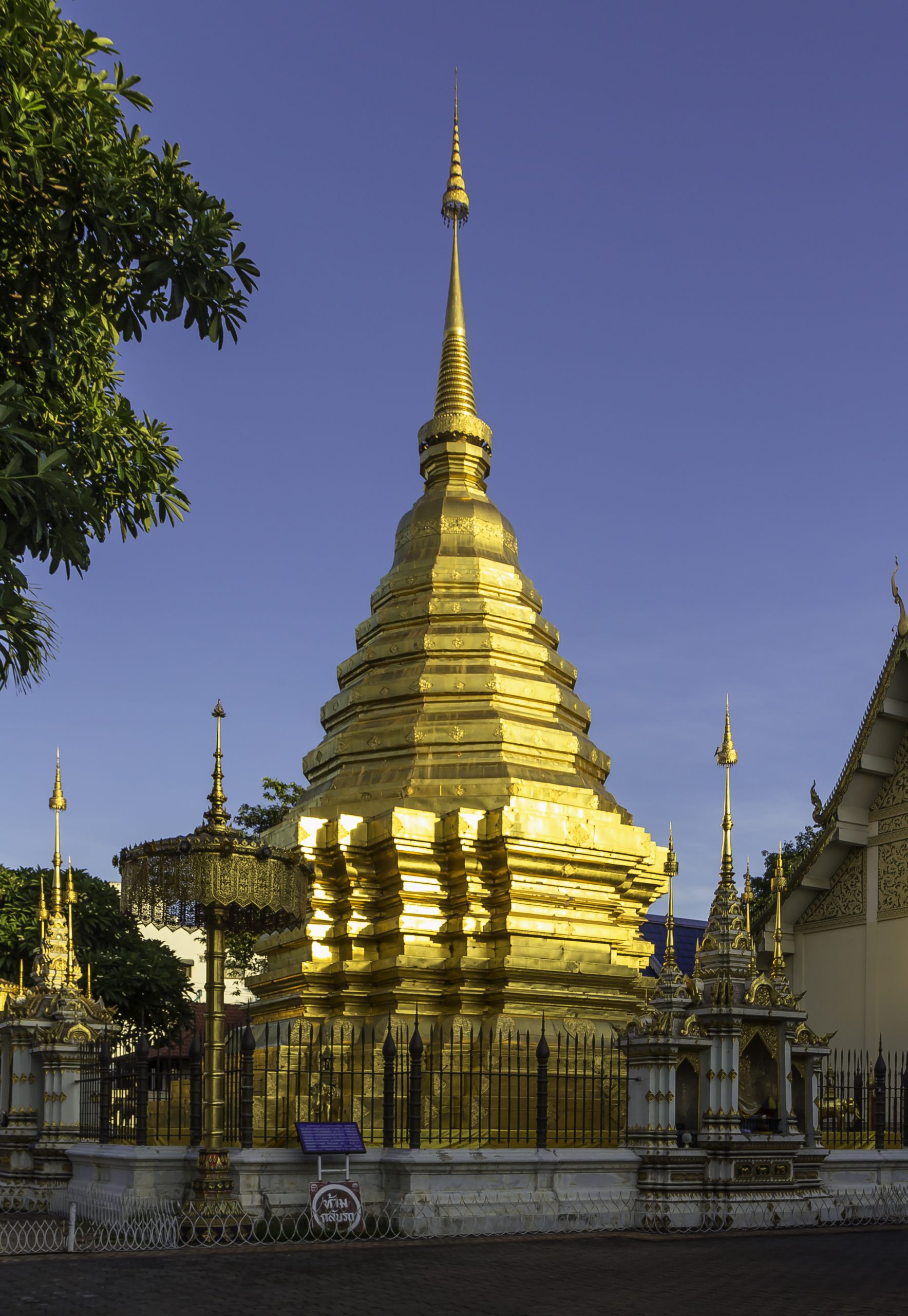 清迈 Wat Chom Phu 金色佛塔的折角塔身、层叠基座和细长塔尖,外围有黑色围栏