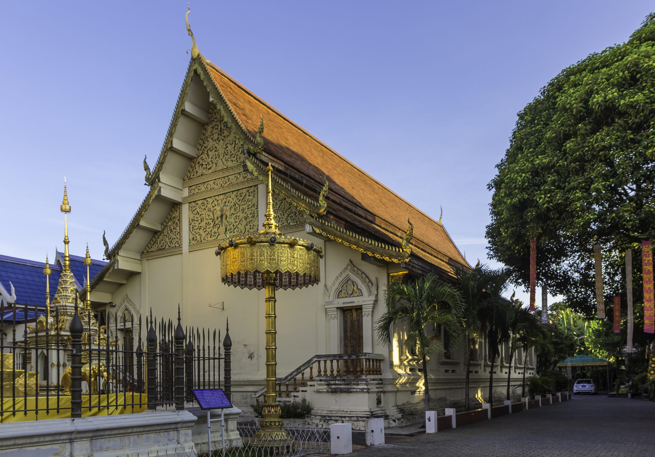 清迈 Wat Chom Phu 白墙殿堂的橙色屋顶、金色山墙与院内伞形装饰