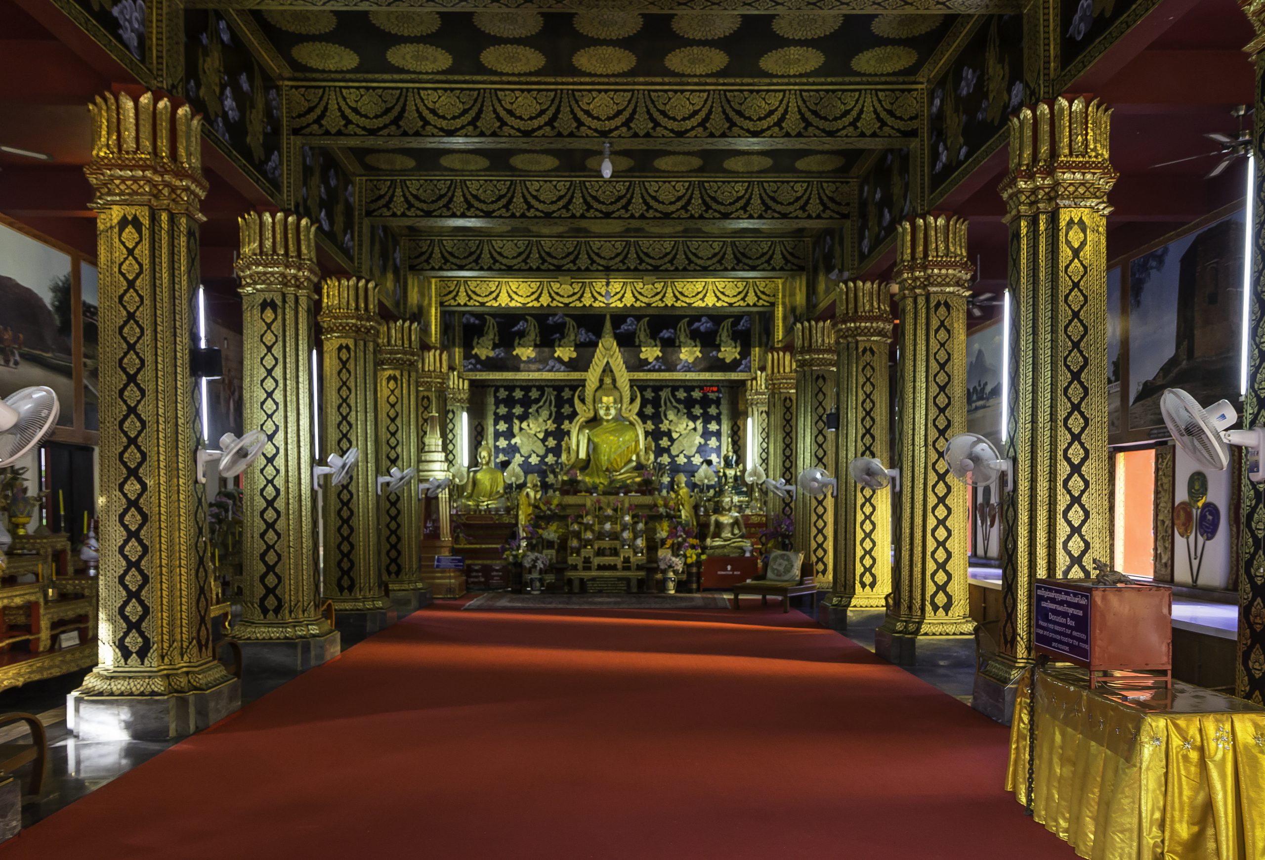 黑底金纹柱列之间，红地毯通向金色坐佛。