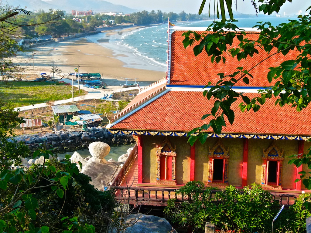 考陶寺院红瓦屋顶后方的弧形沙岸与海边船只